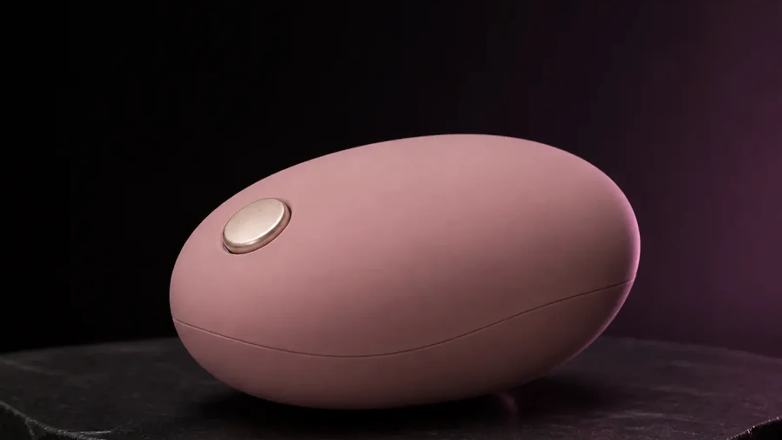 An unbranded app-controlled personal-wellness device beside a charging cable and storage pouch.