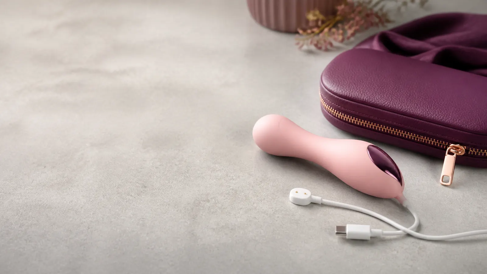 A compact personal wellness device with a USB-C charging cable and travel pouch.