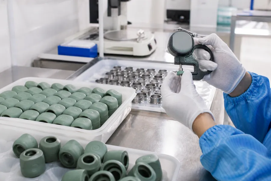 A factory quality-control team reviewing consumer-electronics components and production references.